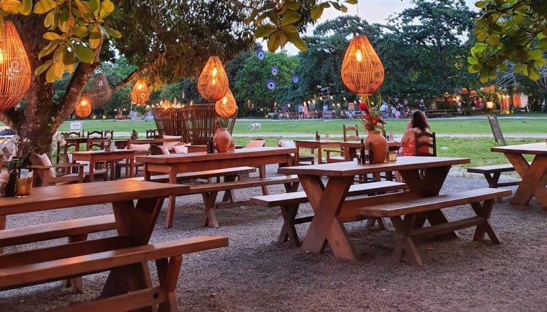 Mesas de madeira em ambiente ao ar livre em Trancoso, iluminadas por luminárias artesanais, criando um clima acolhedor e rústico.