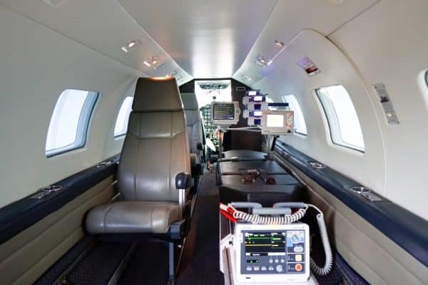 Interior de uma aeronave equipada como UTI Aérea, com poltrona para equipe médica e monitor cardíaco.