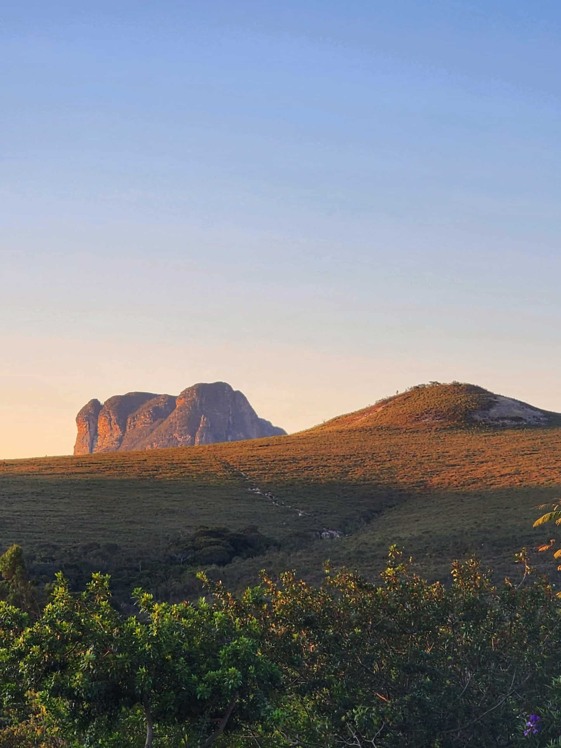 Vista panorâmica do Morro do Pai Inácio ao amanhecer, cercado pela vegetação e campos da Chapada Diamantina sob o céu azul claro.