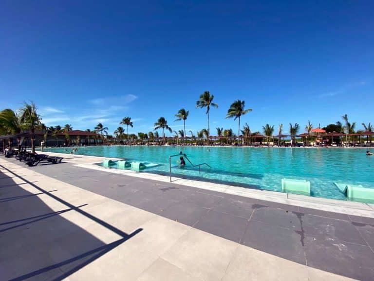 Vista panorâmica da piscina do Resort Vila Galé Alagoas com espreguiçadeiras e palmeiras ao fundo em um dia ensolarado.