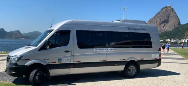 Van de transporte executivo utilizada no serviço de Transfer Aeroporto Galeão para Copacabana, estacionada com o Pão de Açúcar ao fundo.