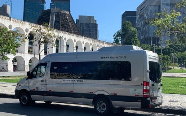 Van da empresa Avante Pax em frente aos Arcos da Lapa, no Rio de Janeiro, oferecendo serviço de transfer com segurança e conforto.