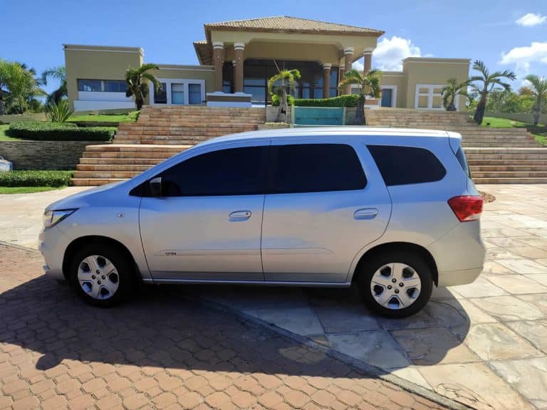 Veículo Chevrolet Spin prateado estacionado em frente a uma mansão, utilizado para transfer privado ao Iberostar Bahia.