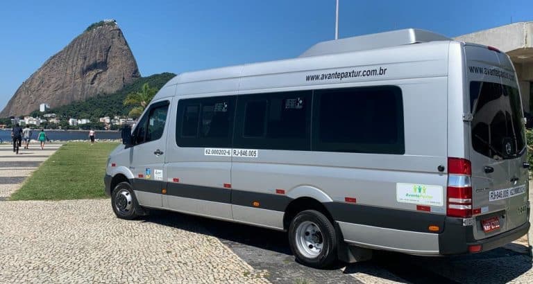 Van de transporte executivo usada no serviço de Transfer Aeroporto Galeão para Copacabana, estacionada com o Pão de Açúcar ao fundo.